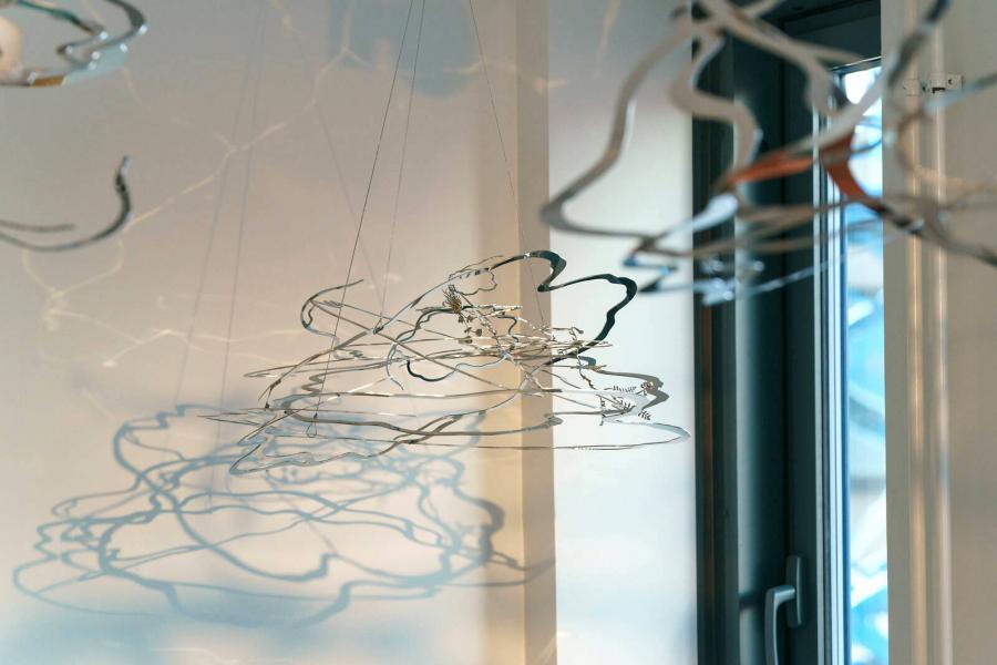 Yksityiskohta Kirsi Kaulasen taideteoksesta, jossa metallista valmistettuja elementtejä roikkuu katosta.