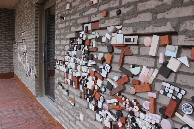 The brick wall is decorated with different colours, shapes and sizes of building blocks.